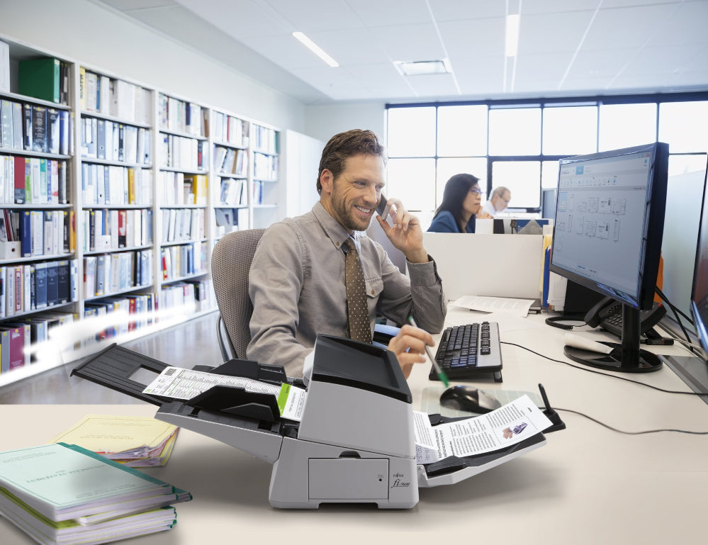 Man sitting at a desk with a computer and printer in an office setting.
