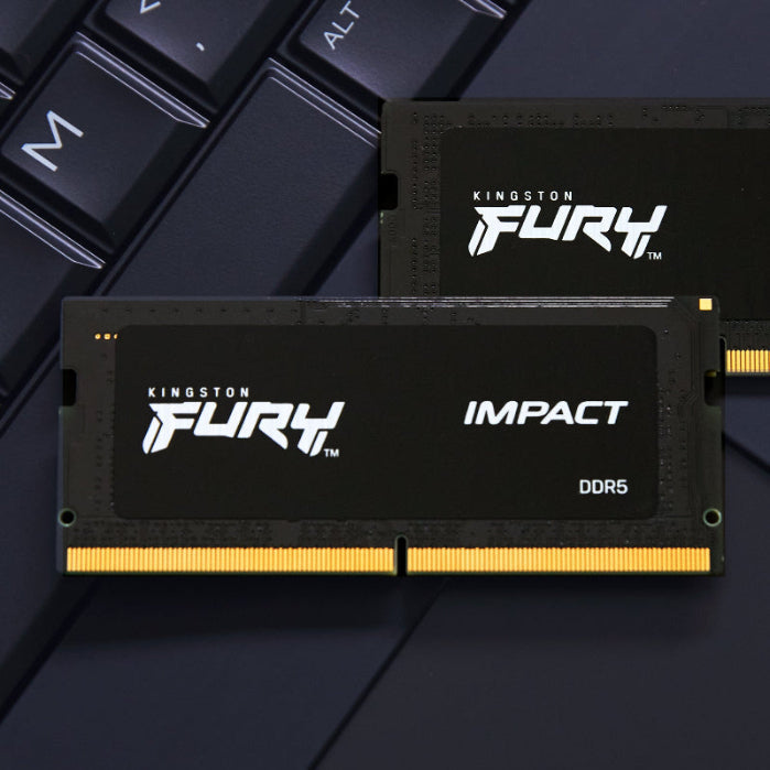 Two Kingston Fury Impact DDR5 memory modules on a dark surface with keyboard keys.