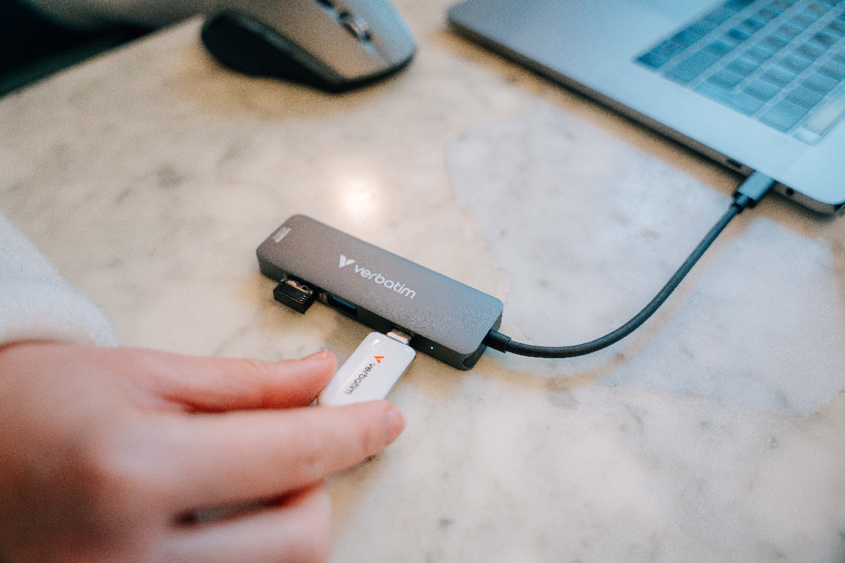 Verbatim USB hub being used on a desk with a laptop and mouse in the background.